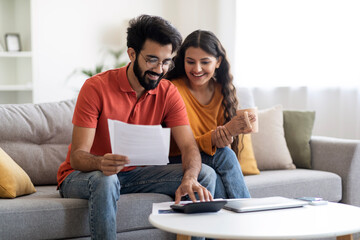 Happy Indian Spouses Checking Financial Documents And Calculating Family Budget At Home