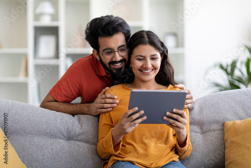 Digital Leisure. Happy Young Indian Couple Using Tablet Computer At Home