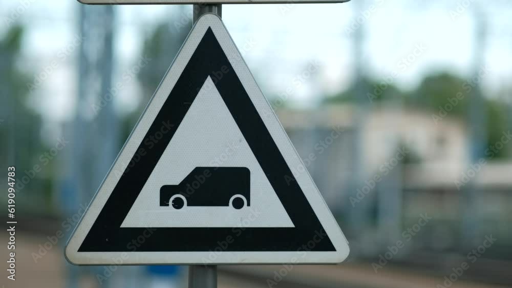 A road sign with a car and a train in the background.