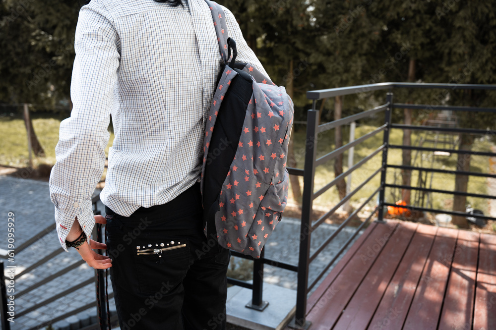 a teenager has a school backpack on his shoulders