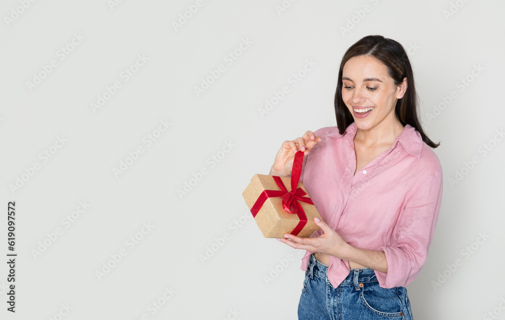 Thrilled woman in pink opening gift box and smiling Thrilled woman in pink opening gift box and smiling