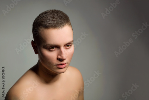 portrait of young woman with short hair and bare shoulder on grey background