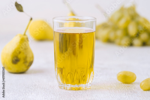 Pears, grapes and juice on white wooden background