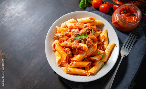 penne pasta in tomato sauce with meat with on dark table