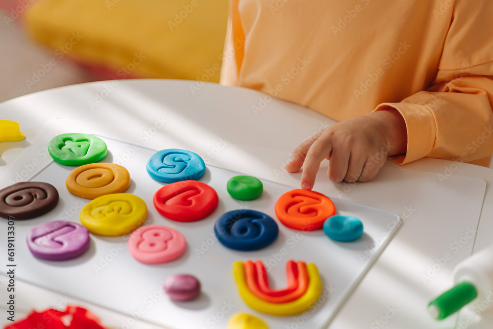 A little girl play with plasticine and creates colorful numbers. Learning to count through play. Early education. Fine motor skills, creativity and hobby. A little girl play with plasticine and creates colorful numbers. Learning to count through play. Early education. Fine motor skills, creativity and hobby.