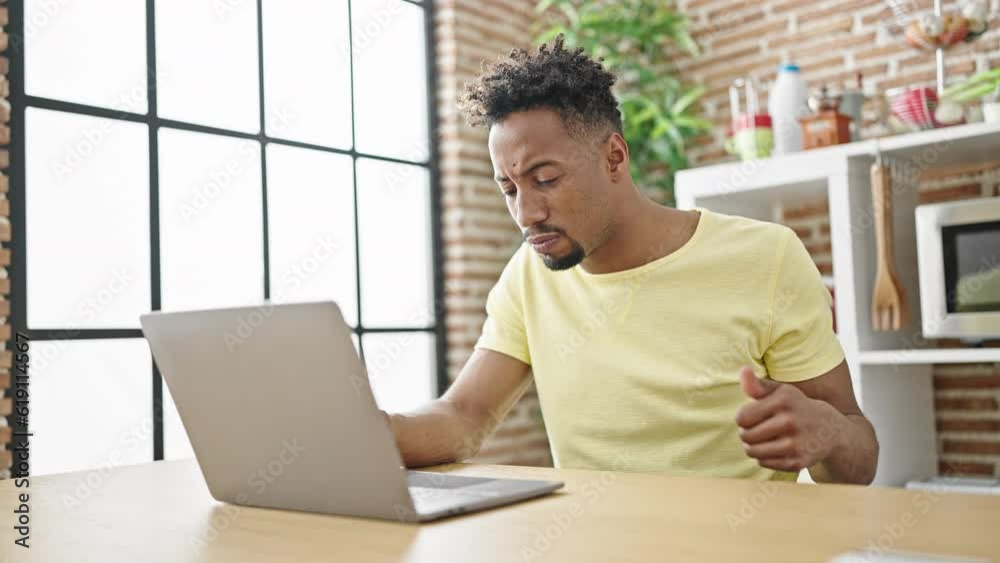 African american man shopping with laptop and credit card looking upset at dinning room African american man shopping with laptop and credit card looking upset at dinning room