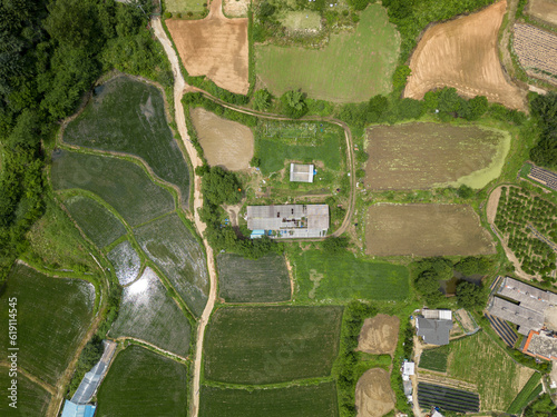 
A photograph captured from a bird's-eye view, showcasing the picturesque Korean countryside, with its focal point being an old, weathered building.