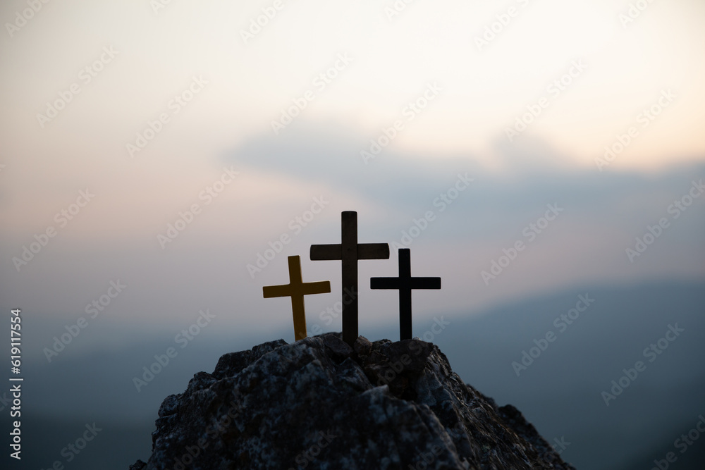 The three holy crosses of Jesus Christ shining through the red sky and clouds and bright rays background. Silhouette cross on Calvary mountain sunset background. Easter concept