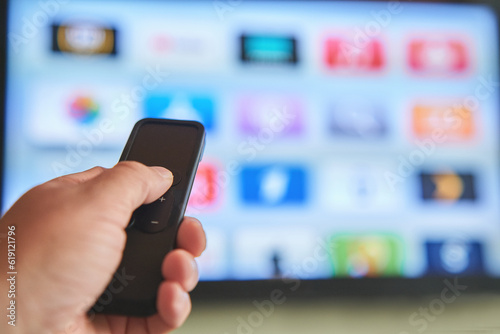 Multimedia streaming concept. Hand holding remote control. TV screen with lot of pictures.