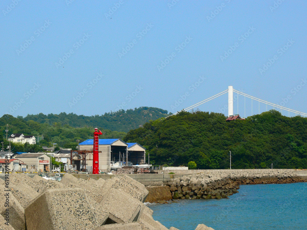 Foto de 瀬戸大橋と瀬戸内海沿岸の漁港入り口。 漁港入り口の赤い防波堤灯台。 向かって右側が赤灯台、灯火も赤色。 do Stock