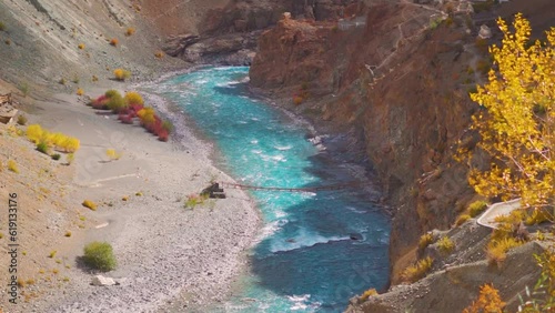 Tsarap Chu river flowing besides the yellow and orange plants during the autumn season as seen during trek to Phugtal monastery in Zanskar, Ladakh, India. River during autumn season. photo