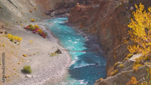 Tsarap Chu river flowing besides the yellow and orange plants during the autumn season as seen during trek to Phugtal monastery in Zanskar, Ladakh, India. River during autumn season. photo