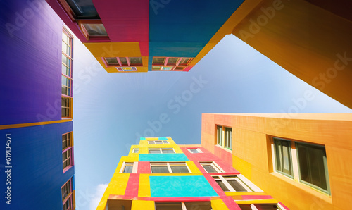 illustrazione Generative Ai con scorcio di cielo limpido circondato da facciate dai molteplici e brillanti colori di alti edifici photo