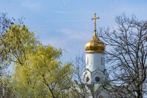 Church saint Nicholas with golden domes and place religion of orthodox christian. Built structure for prayer in modern city. Landscape with green park in middle of river. Monastyrsky island in Dnipro. photo