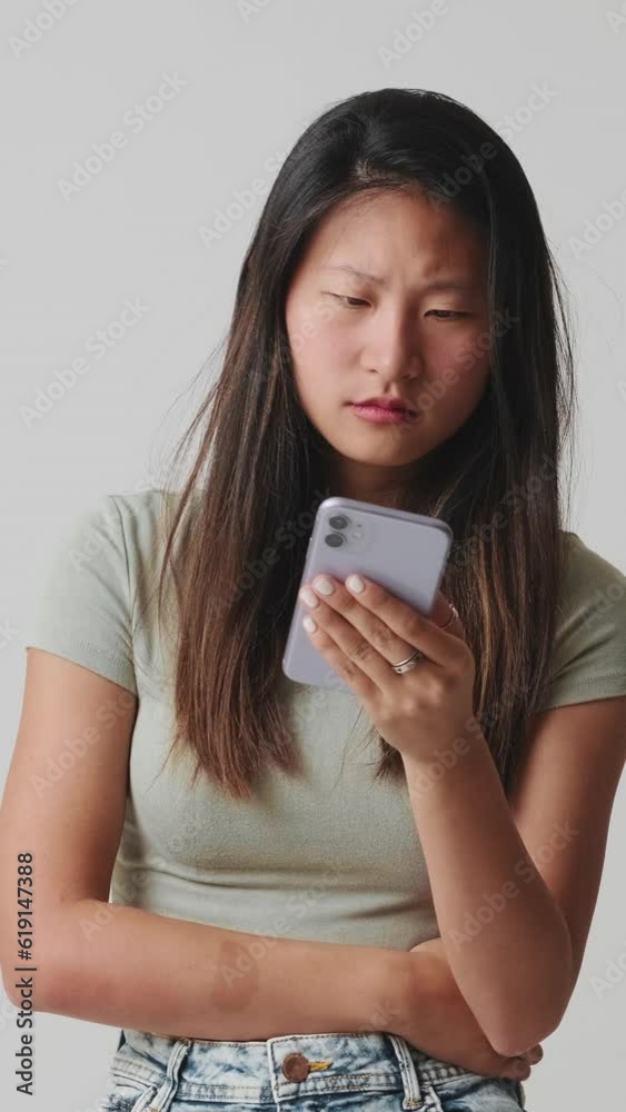 Young woman looking at mobile phone choosing something, isolated over white background in studio Young woman looking at mobile phone choosing something, isolated over white background in studio