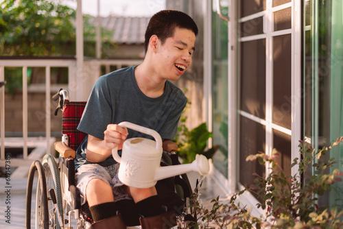 Young man with disability holding white watering can water plants on a wheelchair accessible balcony,Hobby and Rehabilitation with natural therapy,Exercise relaxation,Environmentally friendly concept.