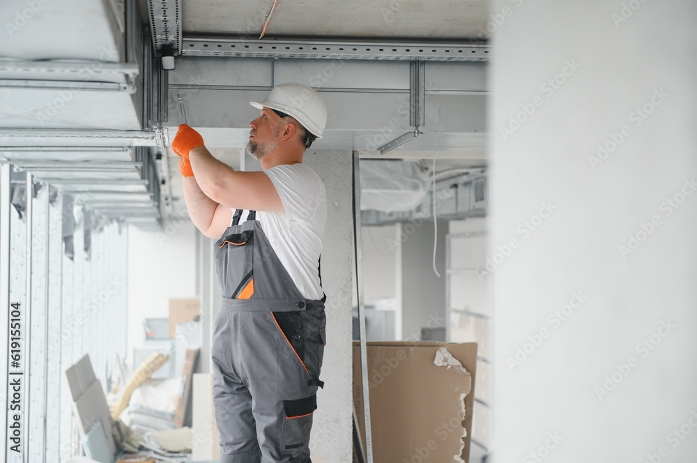 Man setting up ventilation system indoors. A male worker installs air ventilation pipes in a new office building. Man setting up ventilation system indoors. A male worker installs air ventilation pipes in a new office building.