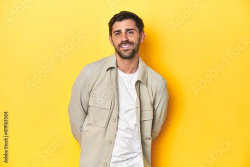 Caucasian man in grey shirt, studio shot on yellow happy, smiling and cheerful.