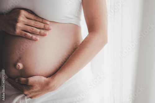 Concept Maternity and Pregnant, Prenatal care and pregnancy. Love of family, motherhood. Pregnant woman is holdings belly and enjoying the care of her child in the morning.
