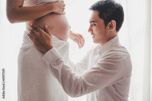 Concept Maternity and Pregnant, Prenatal care and pregnancy. Love of family, motherhood. Pregnant woman and her husband touch and look at the belly side windows at home.