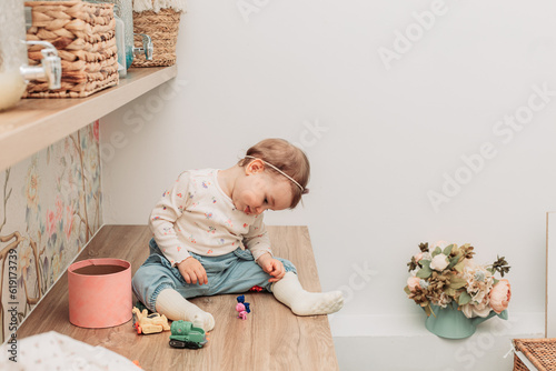 Little baby girl sitting on the table playing with small toys. Copy space