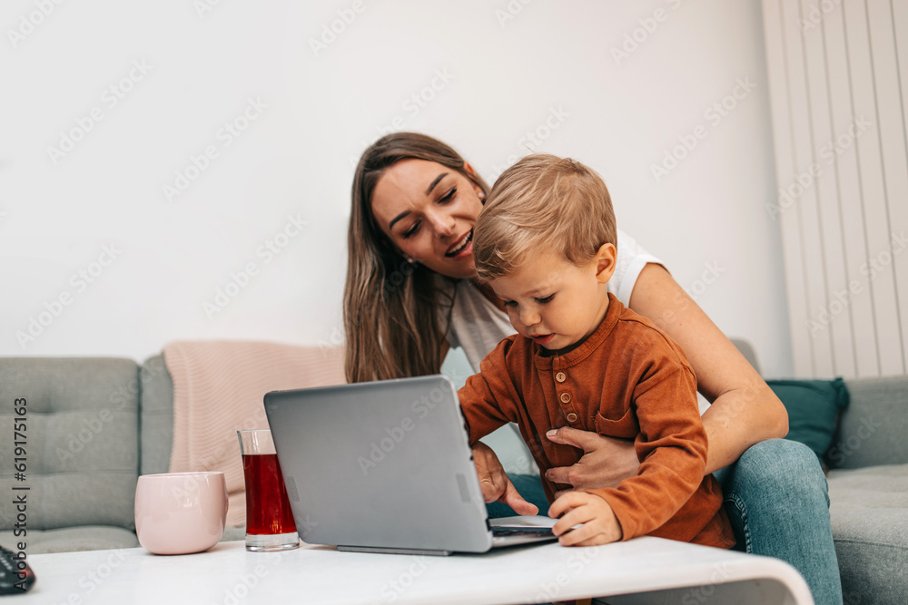 Happy middle age woman playing with her little son at home. They are using smart phone and laptop computer for playing, learning and online surfing. Happy middle age woman playing with her little son at home. They are using smart phone and laptop computer for playing, learning and online surfing.