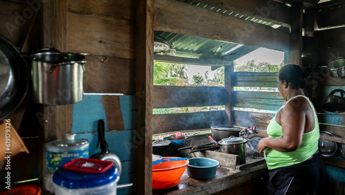 Afro-descendant and mestizo native woman cooking inside her humble wooden house on Nicaragua's Caribbean Coast photo