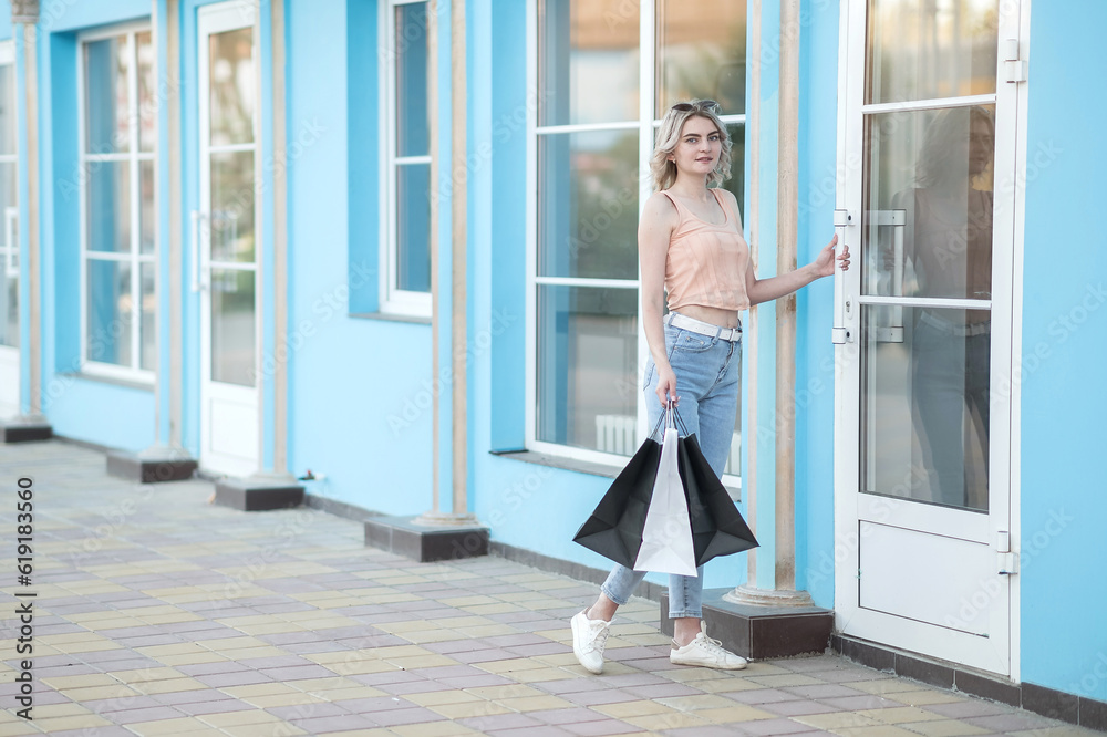 A young girl with packages enters the store. Buying things in the summer. A young girl with packages enters the store. Buying things in the summer.