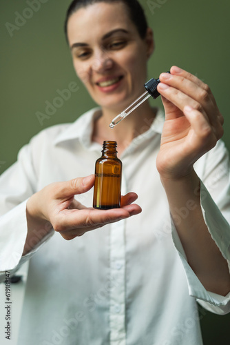 Wallpaper Mural A smiling woman holds a brown bottle of essential oil in her hands and with a pipette. Torontodigital.ca