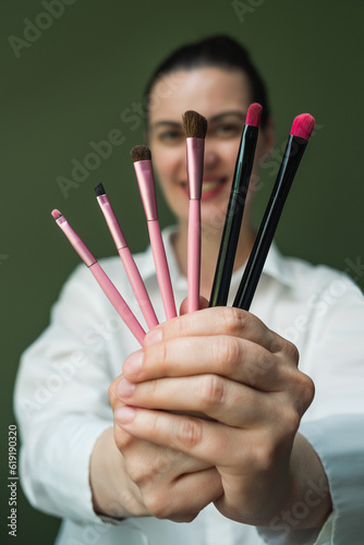 A European woman holds a set of makeup brushes in her hands. A set of makeup brushes in your hands. Makeup artist