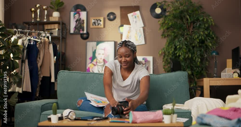 African woman sits comfortably in her living room, completely absorbed in her creative process. She works as a freelance fashion designer, known for her ability to blend diverse styles. African woman sits comfortably in her living room, completely absorbed in her creative process. She works as a freelance fashion designer, known for her ability to blend diverse styles.
