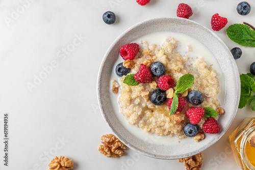 Healthy breakfast. Quinoa porridge with fresh berries, nuts and mint in a bowl on white background. top view