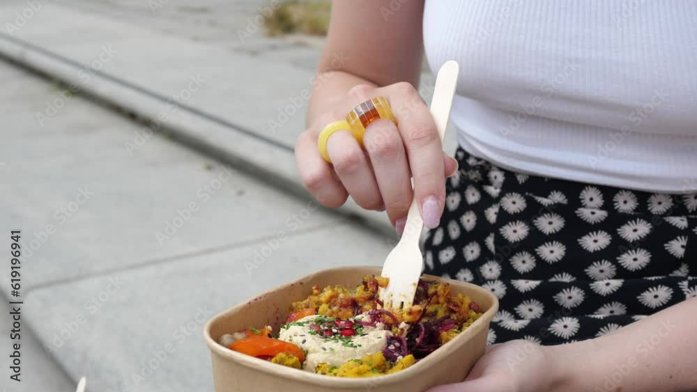 A young woman enjoys a ready-made street food on the street while walking. Healthy snack, healthy eating concept. A young woman enjoys a ready-made street food on the street while walking. Healthy snack, healthy eating concept.