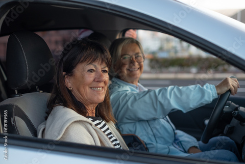 Portrait of two smiling senior women sitting inside the car ready to travel