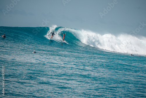 Two Surfer girls on long boards on perfect blue aquamarine wave together, party wave, empty line up, perfect for surfing, clean water, Indian Ocean, Maldives