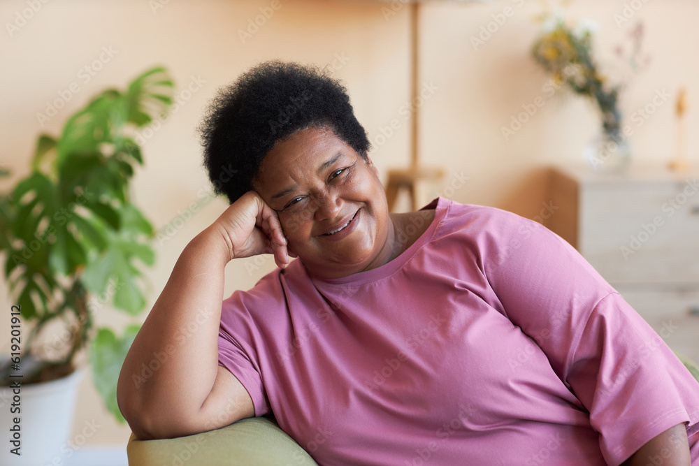 Φωτογραφία Happy African American senior woman in pink t-shirt sitting in armchair in front