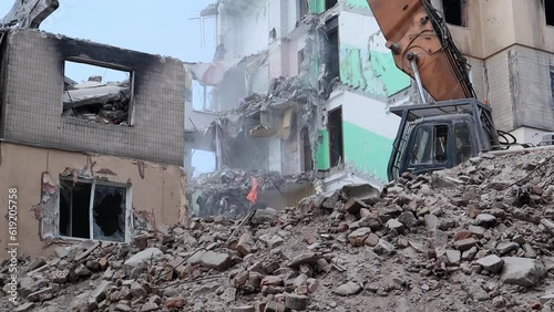 Excavator with hydraulic crusher at the demolition of a residential building. City renewal. Dismantling, destruction of a high-rise multi-storey building for reconstruction. Debris clearing.