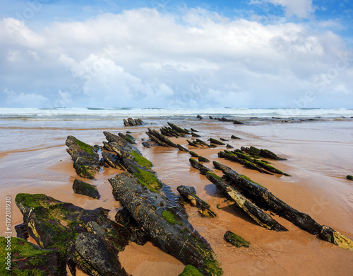 Rock formations on sandy beach and blue sky with cumulus clouds (Algarve, Costa Vicentina, Portugal).