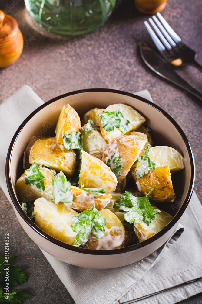 Delicious potato salad with parsley and mayonnaise in a plate on the table vertical view Delicious potato salad with parsley and mayonnaise in a plate on the table vertical view