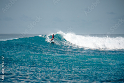 Surfer girl on long board on perfect blue aquamarine wave, empty line up, perfect for surfing, clean water, Indian Ocean, Maldives 