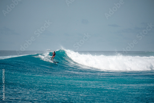 Surfer girl on long board on perfect blue aquamarine wave, empty line up, perfect for surfing, clean water, Indian Ocean, Maldives 