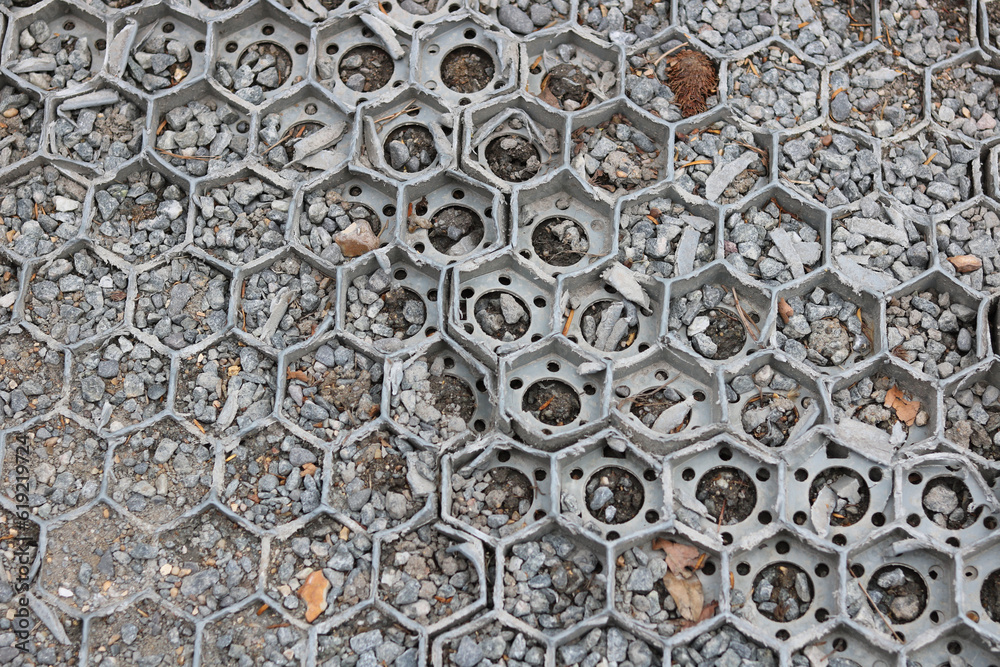 Plastic and gravel hardstanding over grass with hexagonal design - image