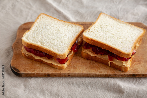 Homemade Peanut Butter and Jelly Sandwich on a rustic wooden board, side view.