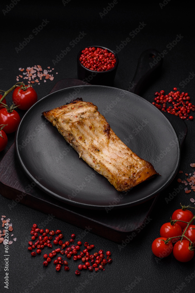 Slice of delicious baked fish with salt, spices and herbs on a ceramic plate