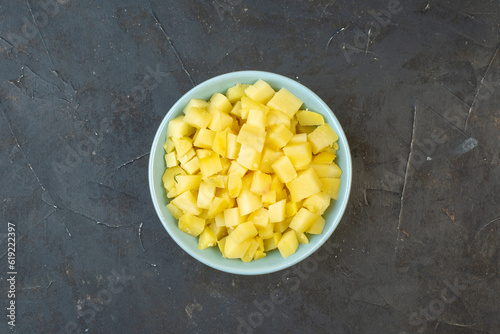 Horizontal view of chopped boiled potatoes in a bowl on dark color table with free space