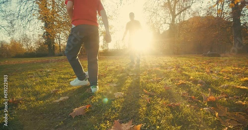 Father and Son playing football, family fun outdoors players in soccer in dynamic action have fun playing football in the grass, sunny day under sunlight.