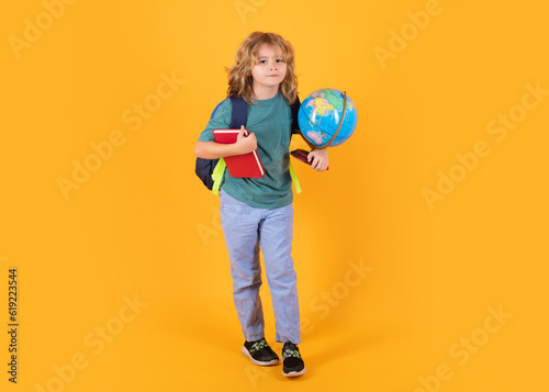 School boy with backpack. Little student on yellow isolated background. Learning, education and knowledge. © Olena