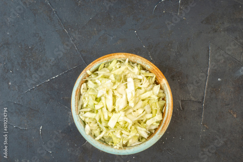 Horizontal view of white cabbages in a bowl on dark color background with free space