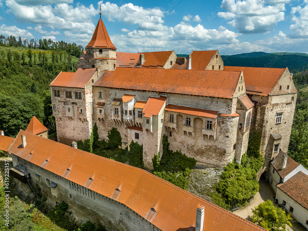 Aerial view of Pernstejn castle with Gothic palace red roof, rectangular and round towers, barbican, forward gun platform in Moravia Aerial view of Pernstejn castle with Gothic palace red roof, rectangular and round towers, barbican, forward gun platform in Moravia