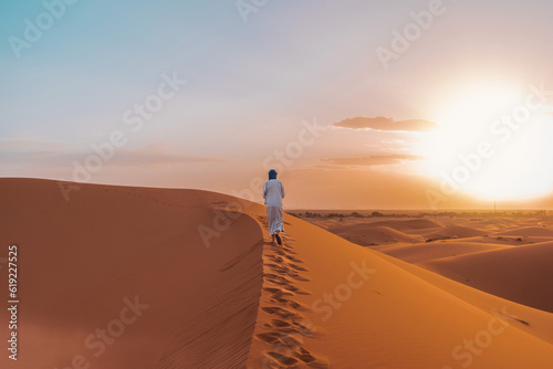 Anonymous Berber person walking on sand in desert photo